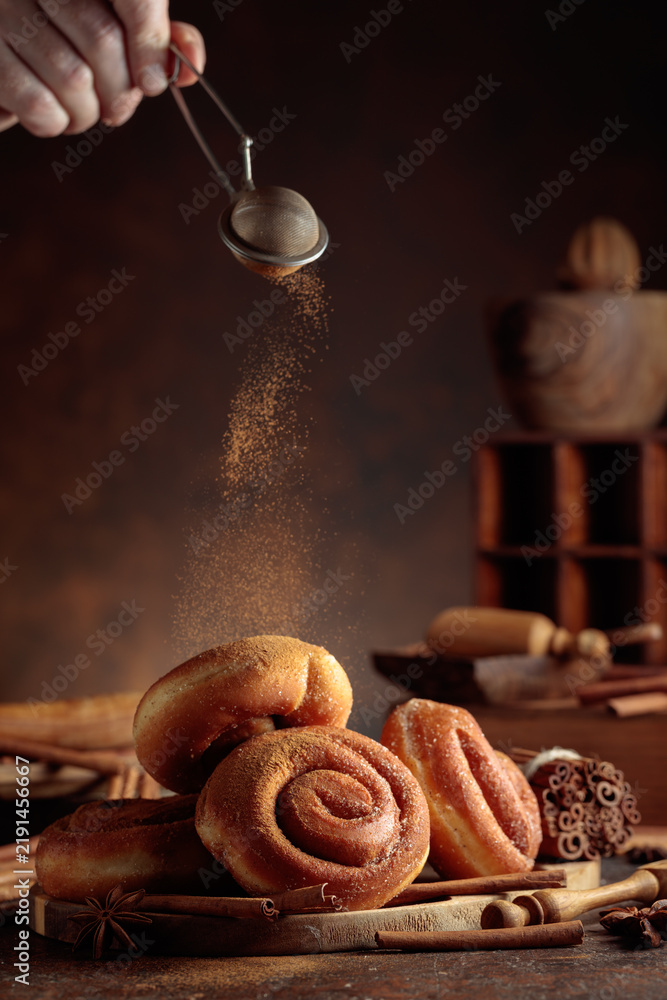 Obraz premium Freshly baked doughnuts are sprinkled with ground cinnamon.