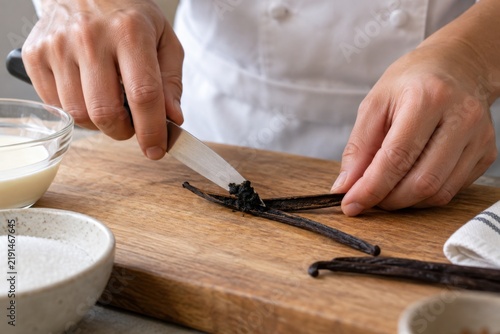 Chef scraping vanilla seeds from a pod on a board
