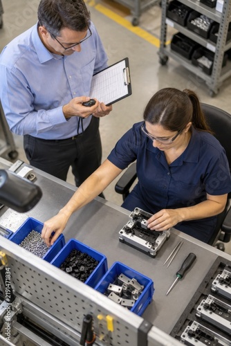 Supervisor timing an assembly task on a factory floor
