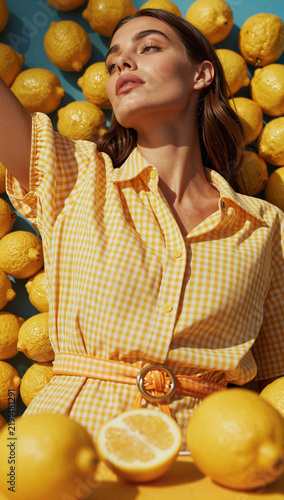 Woman in yellow plaid shirt surrounded by lemons.