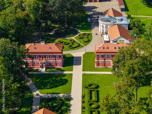 Aerial view of Raudondvaris Manor featuring historic red-brick buildings, manicured gardens, and lush green trees in Raudondvaris, Kauno apskritis, Lithuania.
