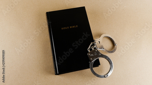 Foto Holy Bible with metal handcuffs on a neutral background, representing law, justi