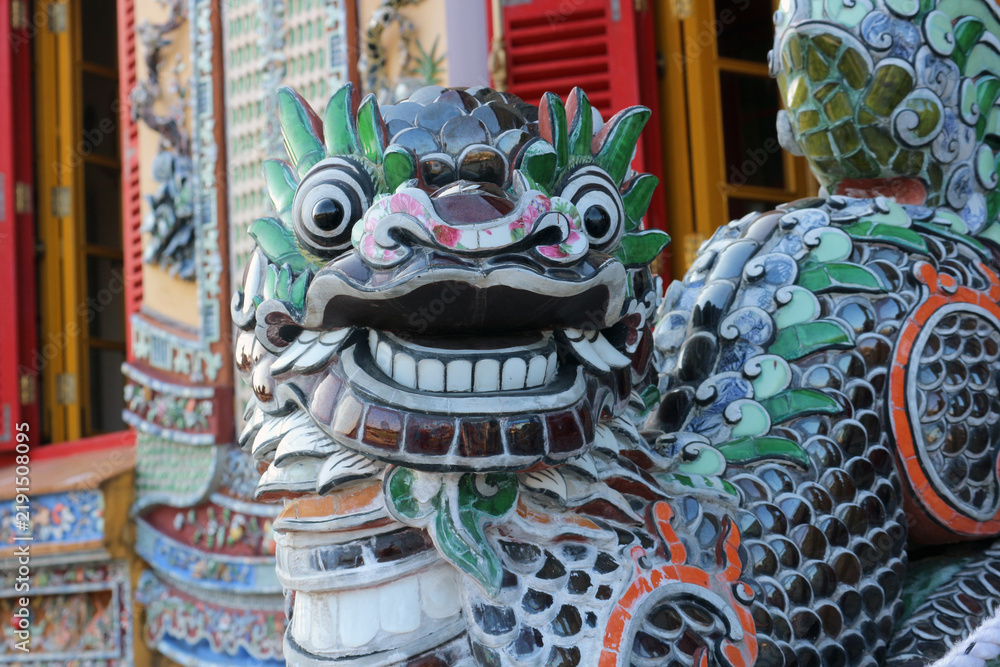 Fototapeta premium Traditional imperial dragon mosaic porcelain shards sculpture close up, oriental ceramic artwork design on weathered temple facade.