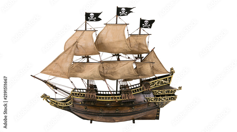 Obraz premium Detailed wooden pirate ship model with fabric sails and black skull flags