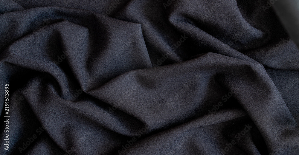 Fototapeta premium Crumpled black fabric texture with soft drapery and waves