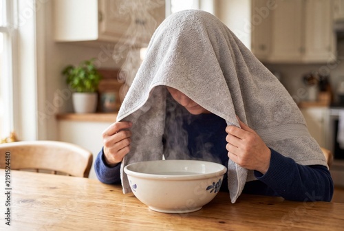 Person inhaling steam from a bowl of hot water with a towel over their head