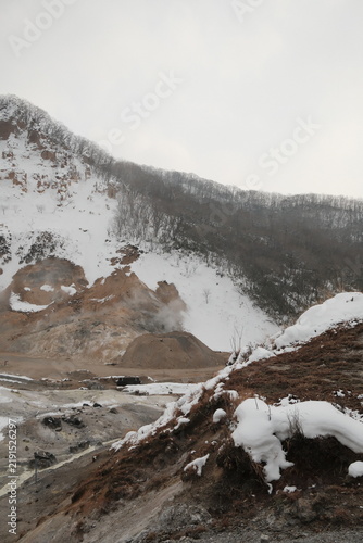 фотографія Snowy volcanic hillside with exposed mineral coloured earth