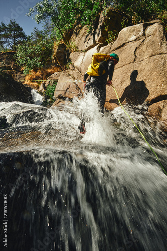 Canvastavla Canyoning adventurer rappelling down a powerful cascading waterfall