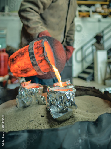 Canvastavla A foundry worker pours intensely glowing molten metal from a heat-scorched cruci