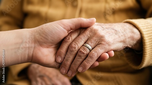 Close up of a young person holding the hand of a senior woman showing care and support