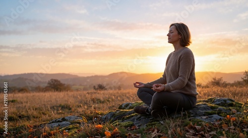 Woman meditating in lotus pose outdoors on a hill at sunrise. Person practicing mindfulness and yoga meditation during autumn equinox