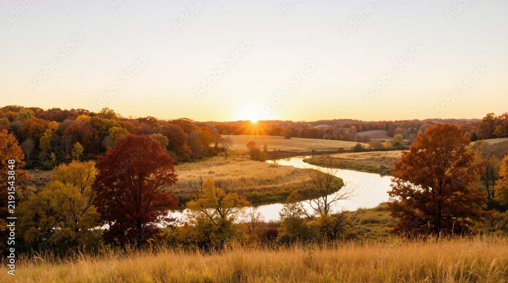 Obraz premium Sunset over a winding river in an autumn landscape. Sunburst on the horizon across colorful fall foliage and rolling hills. Autumnal equinox scenic countryside view