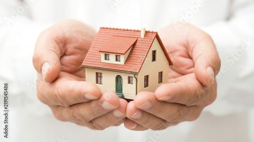 Hands holding small model house as concept for real estate property investment and home ownership protection