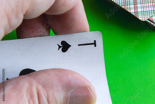 фотографія Closeup Hand Holding Ten Of Spades Playing Card Over Green Table During Poker Ga