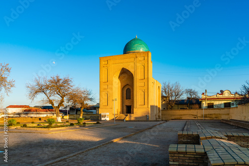 People-free view of the Bibi-Khanym Mausoleum in Samarkand, Uzbekistan, seen from its open courtyard. The historic brick structure features a turquoise-green dome, a tall pointed entrance arch.