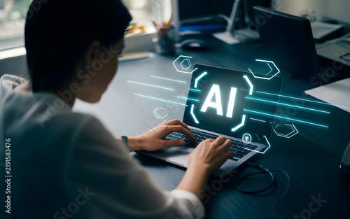 AI Interface on Laptop: A person's hands type on a laptop with a glowing AI interface displayed on the screen, symbolizing the integration of artificial intelligence in modern technology and work.