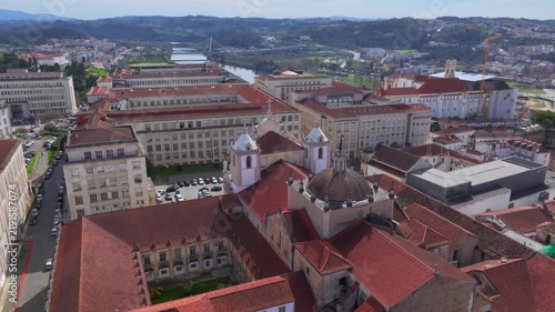 Coimbra city with orange rooftops, historic cathedral, and old buildings under clear blue sky. Aerial Shot in Portugal.