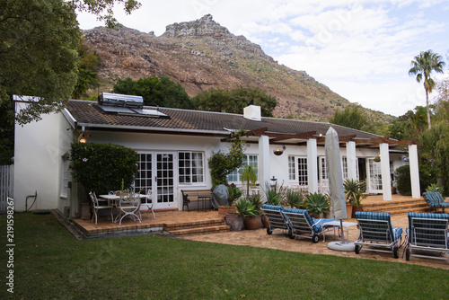 Single-story white house featuring raised brick patio with pergola, French doors, potted succulents
