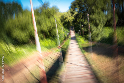 Quadro su tela Sideways motion blur on a suspension footbridge creating a first-person sensation of swaying, staggering, dizziness, imbalance and unstable vision associated with alcohol intoxication