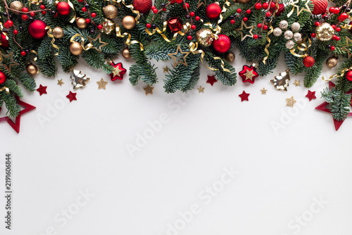 Christmas and New Year frame or border. Festive composition of green fir branches with golden and red decorations on white background.