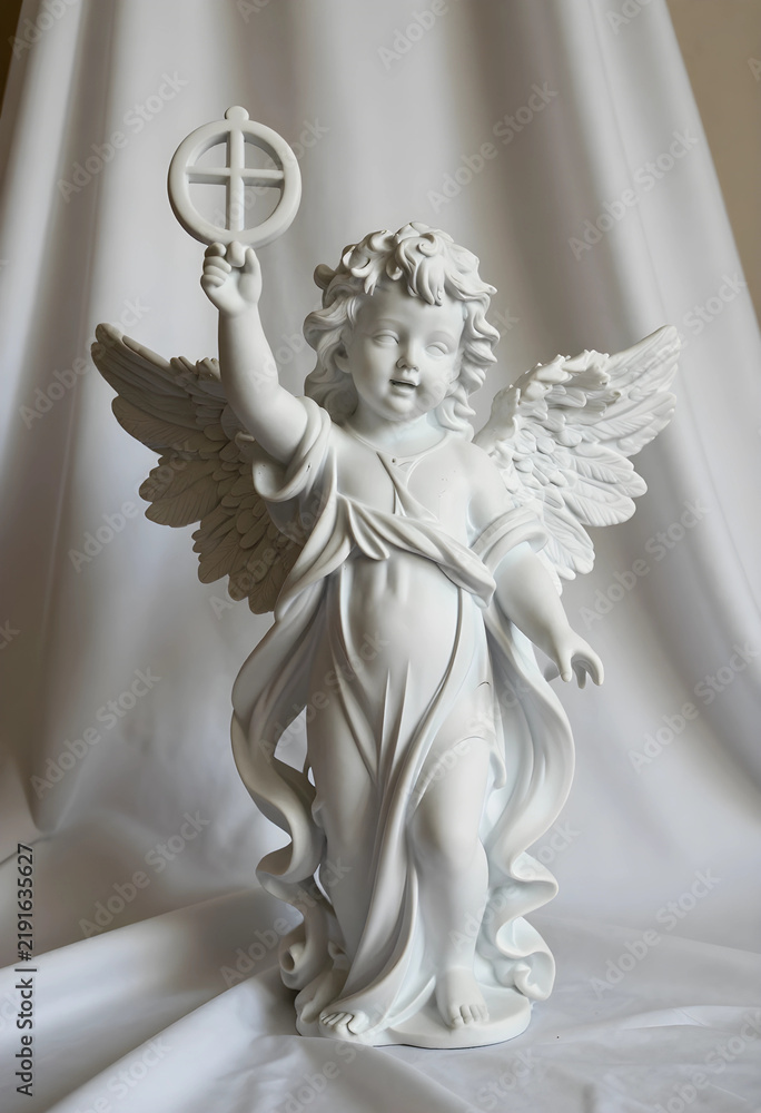 Fototapeta premium Spirituality and faith concept, white ceramic angel figurine holding a cross, religious ornament for baptism or memorial service on soft fabric
