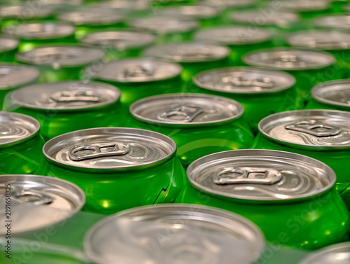 Green aluminum cans of fizzy beverages gathered in packaging on a warehouse shelf, showing a substantial stock of drinks ready for storage and distribution