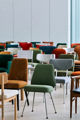Modern colorful chairs arranged in a neat row inside a bright large hal