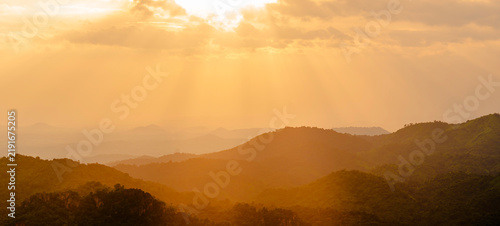 Sunset sky clouds in the Evening over mountain with golden hour orange, yellow sunlight sun dawn, Horizon landscape autumn sun rays sky background