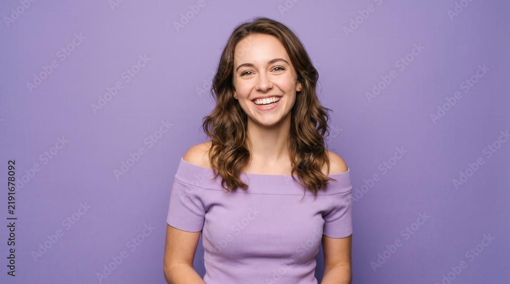 Obraz premium Happy young woman beaming brightly in front of a vibrant purple backdrop