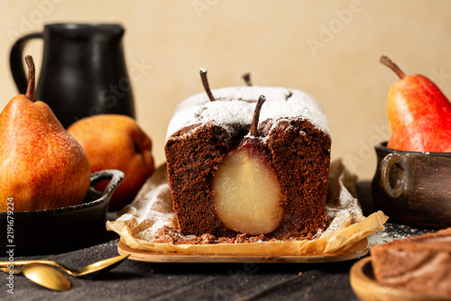 Chocolate Loaf or pound Cake with whole pears. Homemade bakery. Beige background, fresh fruits.
