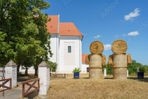 Konstfotografi Traditional white rural church with straw bale figures on well groomed lawn, sum