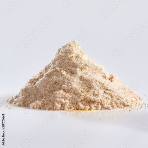 Fine pile of light beige powder on a plain background showcasing texture and detail for culinary or health-related uses
