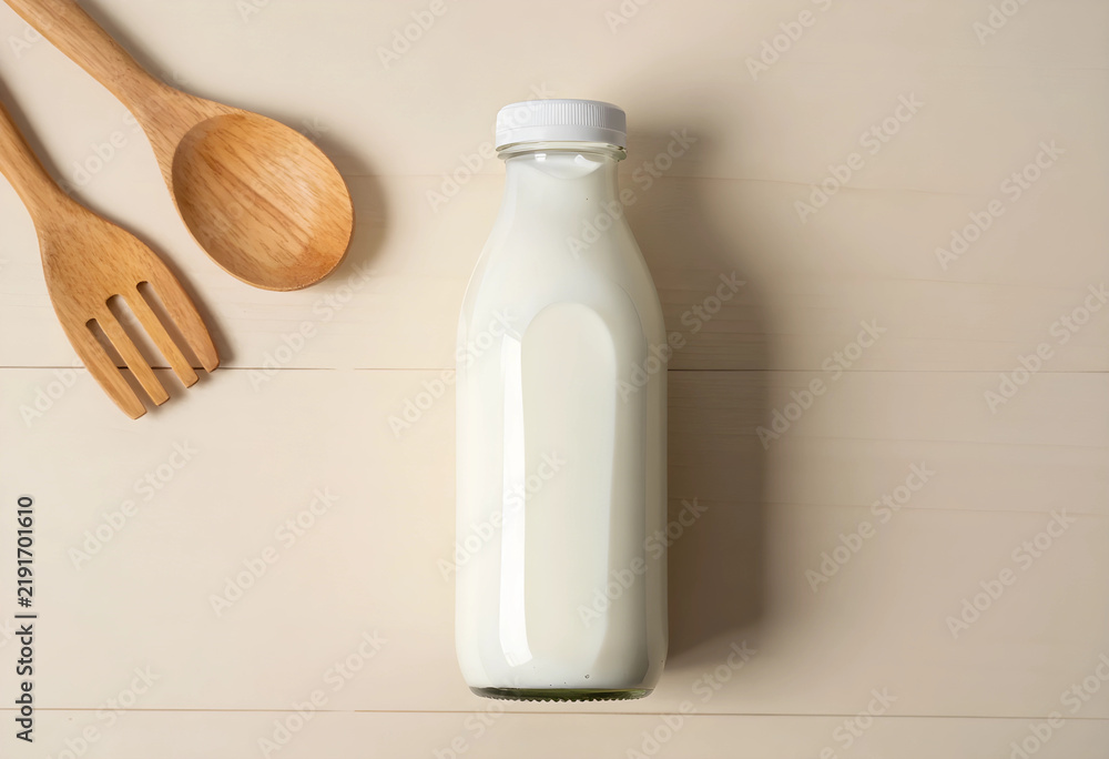 Obraz premium Healthy nutrition and dairy diet, glass bottle of fresh milk with wooden kitchen utensils on a light wooden table for breakfast and organic food