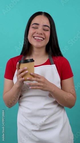 Beautiful young hispanic woman serving a delicious cup of coffee, showing and smiling happily
