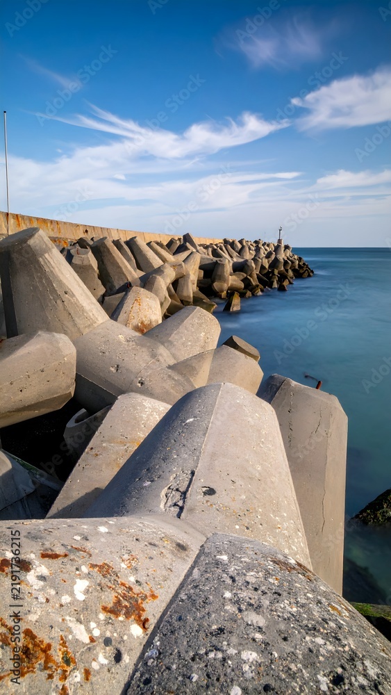 Fototapeta premium Coastal Breakwater with Large Concrete Tetrapods and Clear Sky