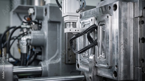 Close up of a heavy duty industrial plastic injection molding machine with a rubber seal being inserted into the mold