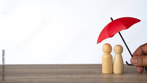 Hand holding red umbrella over two wooden couple figures life insurance relationship protection concept isolated on white background copy space