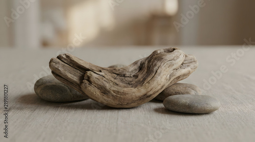 Canvas Print A serene composition featuring a weathered piece of driftwood resting gracefully upon smooth river stones on a textured linen surface, creating a minimalist and calming natural still life display