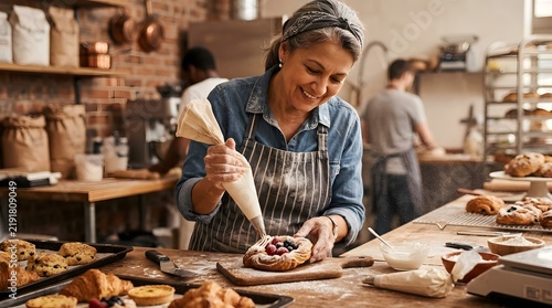 Baker decorating cake in family-owned bakery shop, small business