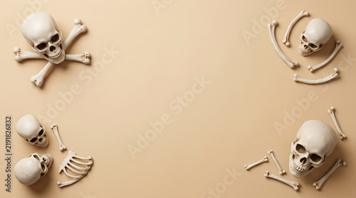 Human skulls and bones arranged as a frame on a beige background with copy space