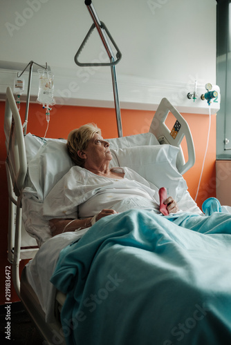 Bild auf Leinwand Senior adult patient resting in hospital bed with IV drip