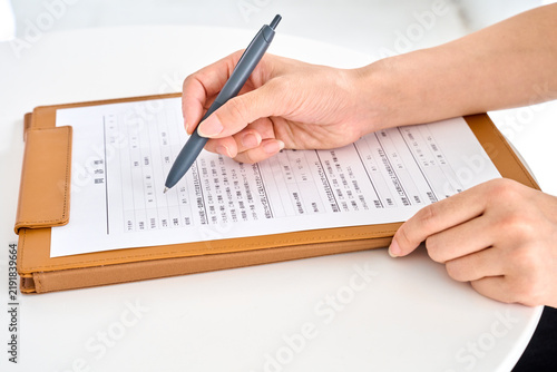 問診票を書く患者の女性の手元