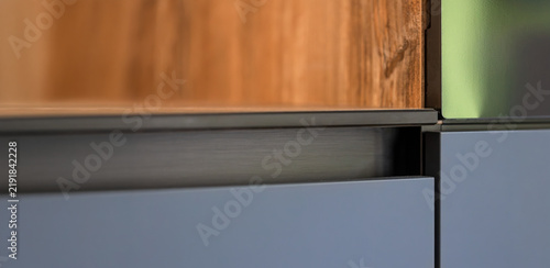 Wood grain and gray kitchen cabinetry detail. Modern fitted interior finish.