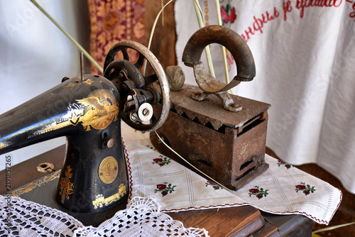 Tapety artystyczne Vintage Sewing Machine and Antique Charcoal Iron on Embroidered Tablecloth