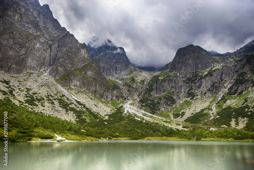 Türkisfarbener Bergsee vor majestätischer Felslandschaft und bewölkten Gipfeln