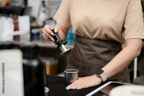 Bild auf Leinwand Espresso preparation concept with a barista holding a coffee tamper at a cafe workstation, representing coffee, tamping, barista, brewing, espresso, precision, preparation