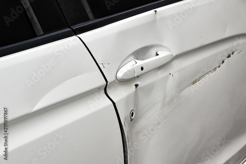 dented and scratched white car door from collision, damaged car body panel caused by minor accident, vehicle repair, insurance claims and automotive maintenance