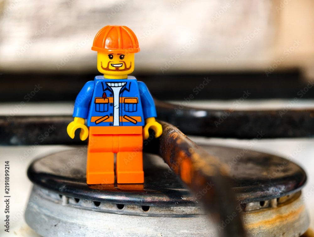 Fototapeta premium Russia, St. Petersburg, August 8, 2020 A Lego minifigure in a construction outfit and hard hat is standing on a gas stove burner.