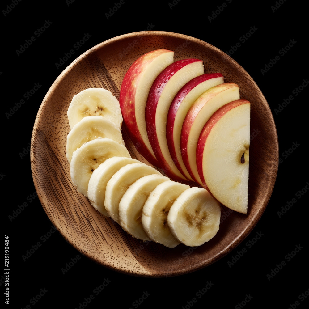 Obraz premium Whole and sliced apple and banana served on round wooden plate, isolated on black background with clipping path