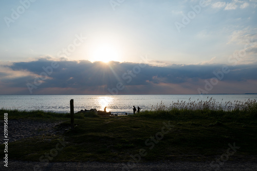 Foto Sunset on a coast with a meadow and the sea.